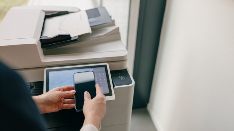 A person using a smartphone to operate a printer
